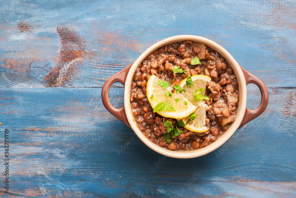 Pot of tasty lentils soup on table