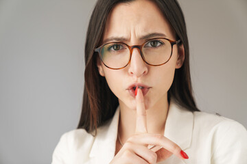 Wall Mural - Photo of irritated businesswoman showing silence gesture on camera