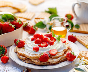 Homemade waffles with whipped cream and fresh strawberries close up view