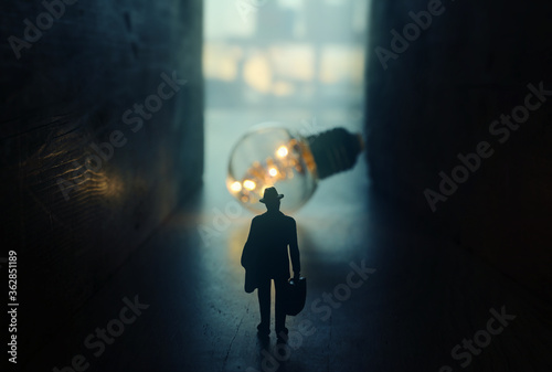 Fotografía Surreal image of person in dark corridor looking at glowing light bulb