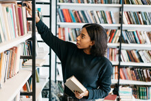 Young Female African American Librarian Making Order On Bookshelves In College, Dark Skinned Woman Student Picking Literature For Education Checking Information In Books Store, Hipster Girl Get Novels