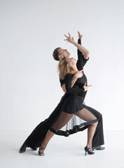 Beautiful couple in stylish dark costumes dancing ballroom dances