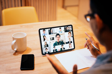 Wall Mural - young man working at home and using tablet computer with video conference