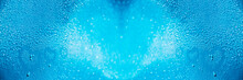 Blue Abstract Background With Bokeh And A Defocus In The Center With Selective Focus On The Sides On Drops Of Water And Painted Hearts On A Wet Glass Surface.