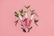© LanaUst - Three lip glosses in different shades of pink decorated with fresh green leaves on pastel pink background. Flat lay style. Organic cosmetics concept. Mockup for your design. Copy space.