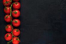 A Truss Of Red Wet Cherry Tomatoes On A Dark Textured Background. Top View. Space For Text.