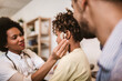 © Mediteraneo - Smiling deaf african american girl with ear implant at doctor's office.