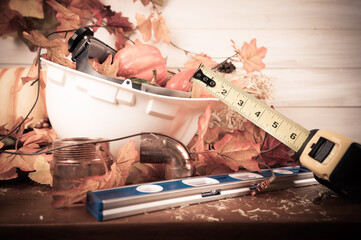 Happy Thanksgiving with construction tools, maple leaves and pumpkin on wood background.
Autumn composition with copy space. Plumber Thanksgiving. 