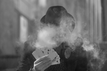 Sticker - Grayscale portrait of a mystical male gamer's hand holding poker cards with smoke in the foreground