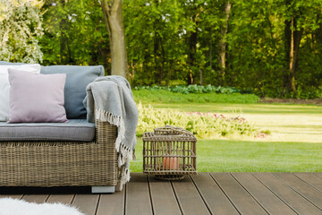 Beautiful green garden with wicker terrace furniture and trees