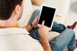 © LIGHTFIELD STUDIOS - Selective focus of man using digital tablet with blank screen on couch