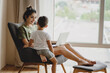 © Olena Bloshchynska - Mother and her son sit together on chair with laptop.