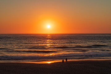 Wall Mural - Orange sunset lights up sky and waves to sandy beach along the Oregon coast