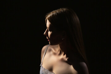 portrait of a young mysterious girl 25 years old on a dark background in contour lighting.modesty an