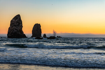Wall Mural - Waves splashing on Sea Stacks with orange sunset lighting up the sky