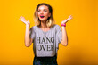 Indoor image of hipster woman posing at yellow background, funny surprised emotions, casual sportive clothes.