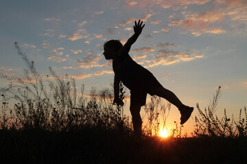 the boy at sunset emits a flight, standing on one leg