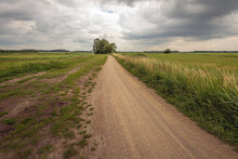 Dramatic Cloudy Sky Over A Winding Gravel Road In A Rural Landscape