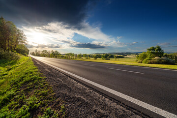 Wall Mural - Empty asphalt road in rural landscape at dramatic sunset