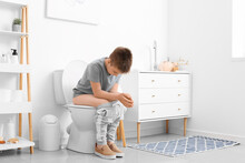Little Boy Sitting On Toilet Bowl In Restroom