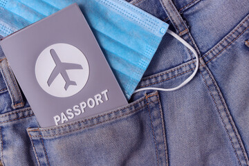  Passport travel with medical mask in jeans back pocket background with copy space. Tourism and traveling concept in New Normal after Covid-19 / Coronavirus pandemic. 