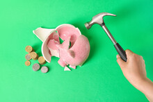 Hand With Hammer And Broken Piggy Bank On Color Background