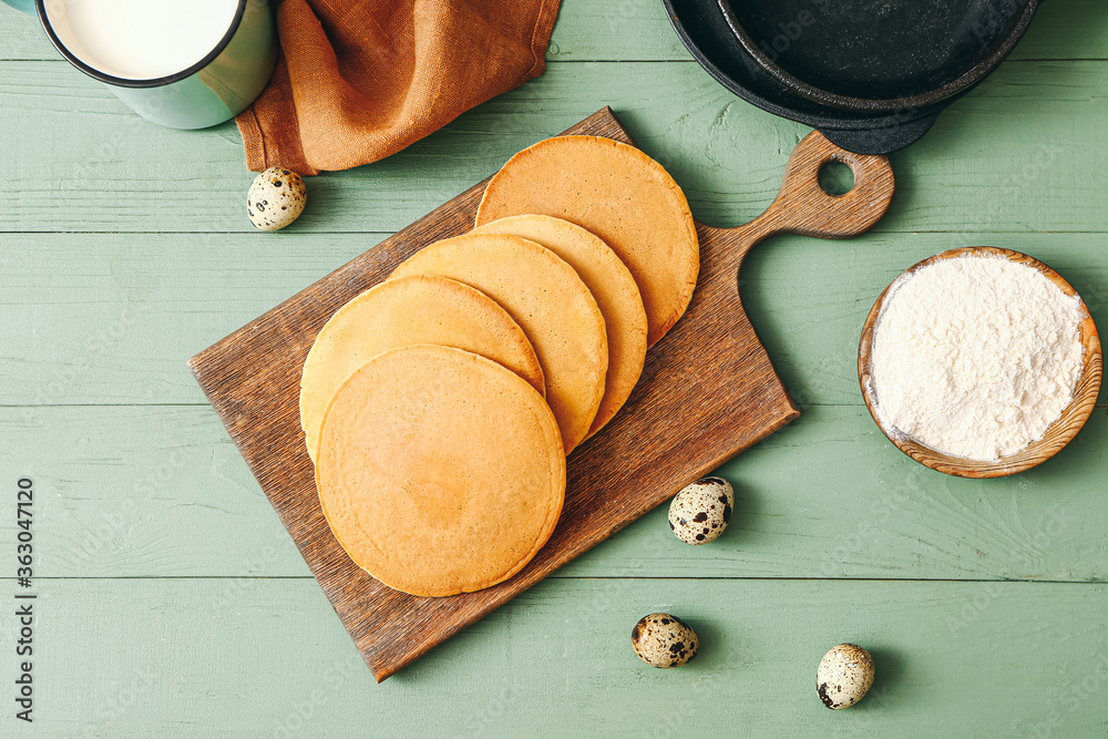 Board with tasty pancakes on table