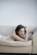 © ImageHit - Woman lying forward on the couch smiling at the camera