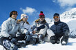 © ImageHit - Friends sitting on snowy ground, laughing happily