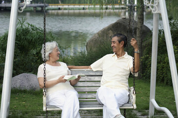 Wall Mural - Senior couple chatting while sitting on a swing