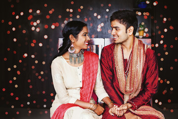 Indian couple in traditional ethnic clothes talking during a festival over bokeh festive background