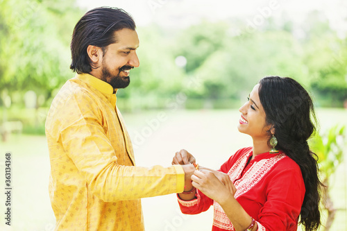 Cuadros en Lienzo Young indian woman tying rakhi on her brother's hand to celebrate Raksha Bandhan
