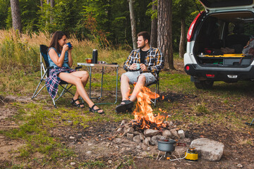 Wall Mural - couple sitting in portable chairs drinking tea talking. camping summer activities