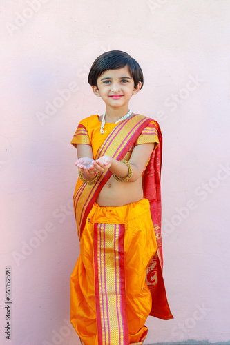Indian little girl in traditional sari and holding oil lamp in Hand celebrating Diwali or deepavali, festival.