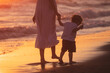 © danieleorsi - A mom with her child walk on the beach of a beautiful shore at the sunset light