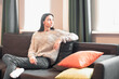 © VERSUSstudio - Young woman pretty relaxing on couch in living room