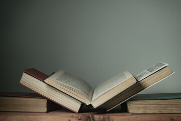 Poster - Beautiful open books on a old red wooden table and white wall background.