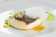 Baked turbot fillet on a white plate. Delicious fish meal with herbs and served with pea puree. Studio shot.
