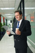 © ImageHit - Businessman holding clipboard and a cup of coffee