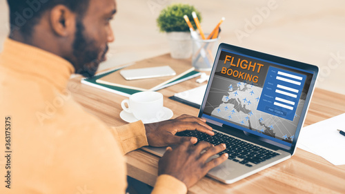 African Businessman At Laptop Booking Flight Sitting In Office, Panorama