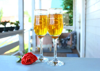 On the summer terrace, two glasses of drink, a rose. Rest and romance.