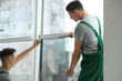 © New Africa - Professional workers tinting window with foil indoors