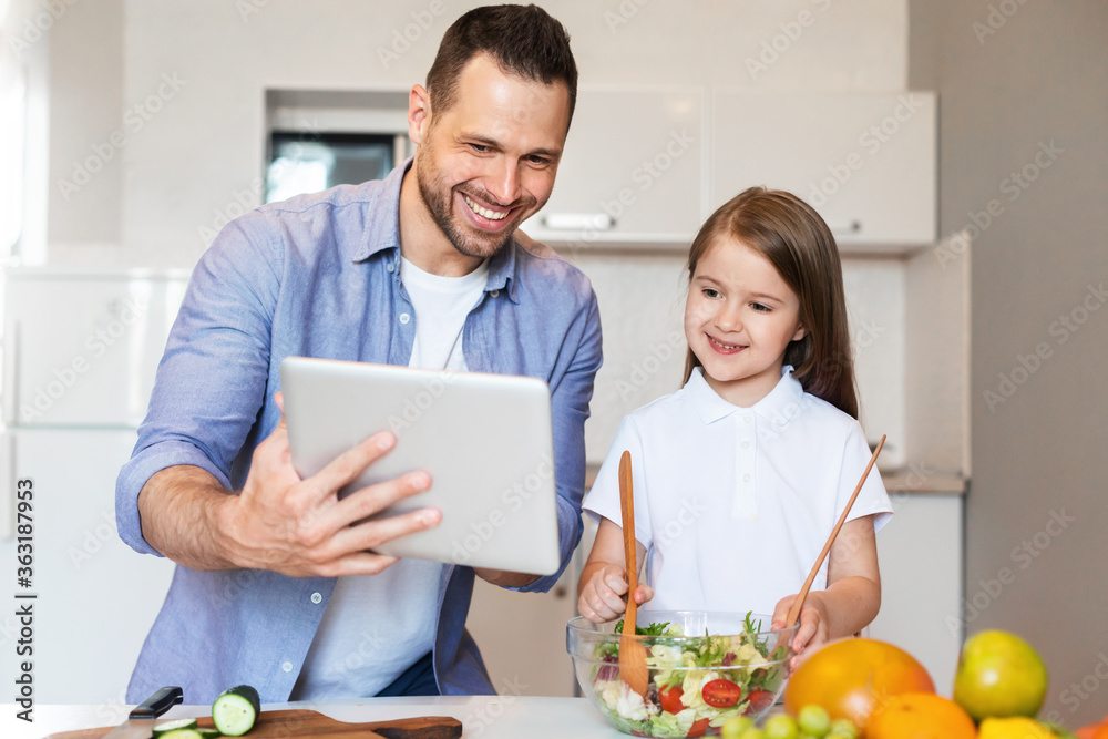 Cheerful Dad And Daughter Cooking Using Digital Tablet In Kitchen - obrazy, fototapety, plakaty 