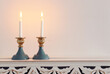 two shabbat candlesticks with burning candles over wooden table