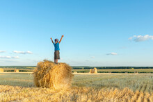 Child Have Fun  Stands  On A Haystack On A Sunny Day In The Field.