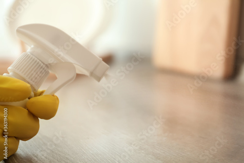 Cuadros en Lienzo Person in gloves spraying detergent onto wooden table indoors, closeup