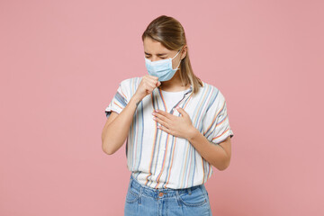 Wall Mural - Sick young blonde woman in striped shirt sterile face mask isolated on pink background. Epidemic pandemic rapidly spreading coronavirus 2019-ncov sars covid-19 flu virus concept. Coughing or sneezing.