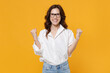 © ViDi Studio - Joyful young brunette business woman in white shirt glasses isolated on yellow wall background studio portrait. Achievement career wealth business concept. Mock up copy space. Doing winner gesture.