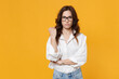 Dissatisfied young brunette business woman in white shirt glasses isolated on yellow wall background studio portrait. Achievement career wealth business concept. Mock up copy space. Clenching fist.