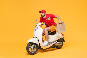 Wall Mural - Delivery man in red cap t-shirt uniform driving moped motorbike scooter hold craft paper packet with food isolated on yellow background studio Guy employee working courier Service quarantine concept